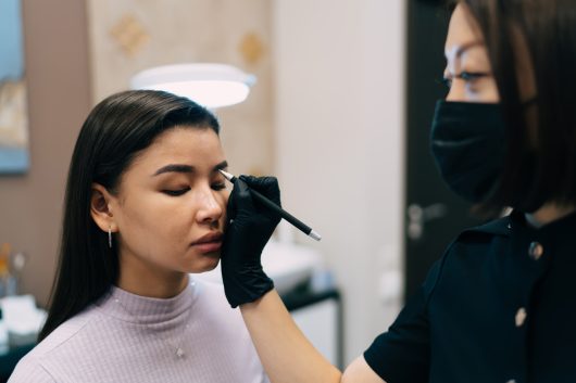 Beautician do eyebrow microblading of asian girl