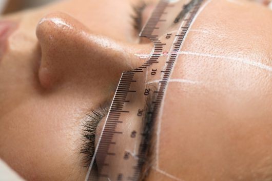 Woman during professional eyebrow mapping procedure